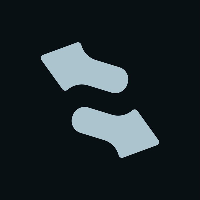 A minimalist logo featuring two light blue-gray angled shapes resembling socks or arrows pointing inward against a dark gray background.