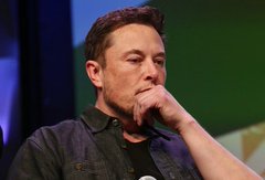Elon Musk sits with his hand thoughtfully resting against his chin, appearing contemplative and serious. His pensive expression fits the post's playful yet pointed question about AI risks, suggesting he might be considering the weight of such concerns himself.