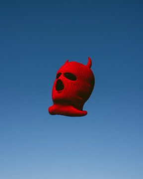 A red 3D-rendered skull with horns floats against a blue sky, matching the playful "feels good man" sentiment of the tweet promoting the artist @danielkoeth's NFT art for bidding.