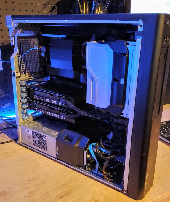 An open computer case displaying dual EVGA GeForce RTX graphics cards and a custom loop liquid cooling system with blue illuminated coolant.