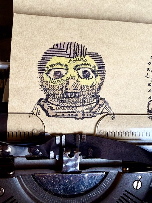 A vintage typewriter with a piece of paper showing a creative illustration of a bearded face composed of typography and decorative patterns, including words like 'toads' and 'mannibal'.