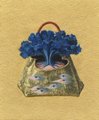 A blue handbag-shaped basket filled with vibrant blue cornflowers sits on a textured yellow background, with a painted landscape of trees and a small structure visible on the basket's surface. The handcrafted artwork, tagged "QT your Tezos Art," showcases a whimsical floral arrangement that combines fashion-inspired design with rustic, nature-themed artistry.
