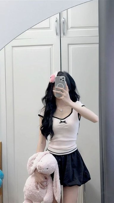 The image doesn't appear to relate to the technical post about blockchain nodes and decentralized ledgers. Instead, it shows a mirror selfie of a person with long dark hair wearing a pink top, black shorts, and a pink hair accessory, holding a stuffed bunny plushie and a smartphone in front of white closet doors.