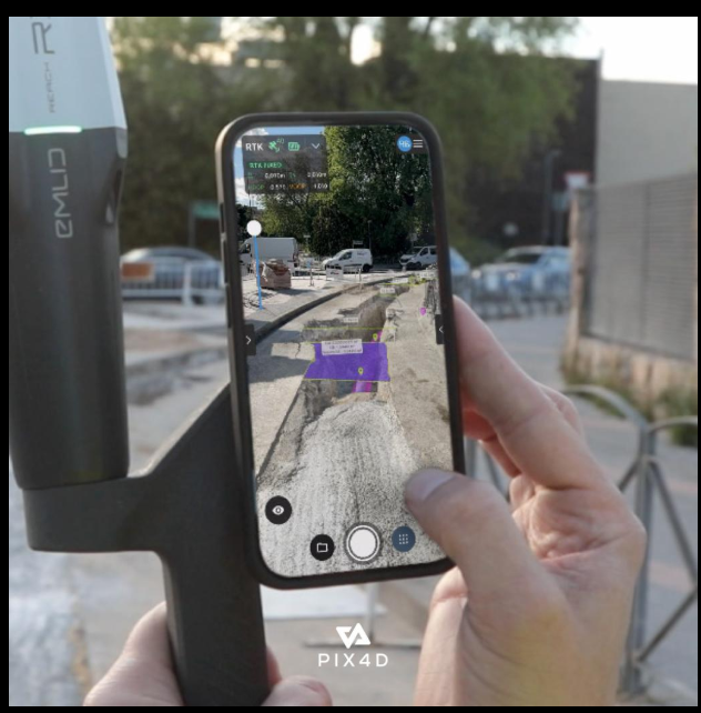 A close-up shows hands holding a smartphone that displays an augmented reality interface, with a PIX4D device visible on the left and a construction site scene overlaid on the phone screen.