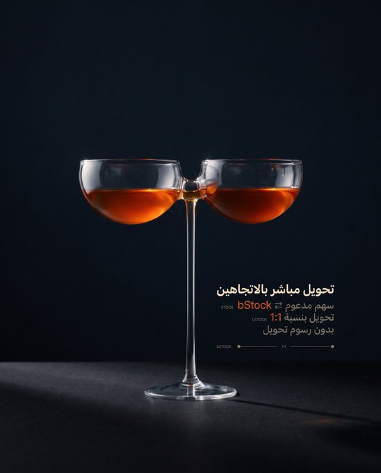 Two coupe glasses filled with an amber liquid clink together against a dark background, with Arabic text overlaid on the right side.