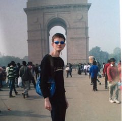 A woman wearing sunglasses stands smiling in front of the India Gate monument in New Delhi, with other tourists visible in the background on a hazy day. The image, paired with the caption "Ethereum vs Robinhood," likely uses the iconic landmark as a backdrop to contrast two popular cryptocurrency and stock trading platforms, perhaps highlighting a personal travel memory amid discussions of financial platforms.