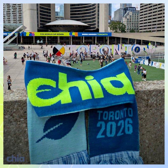 A Toronto 2026 FIFA World Cup branded scarf with 'chia' logo, photographed at Nathan Phillips Square in Toronto.