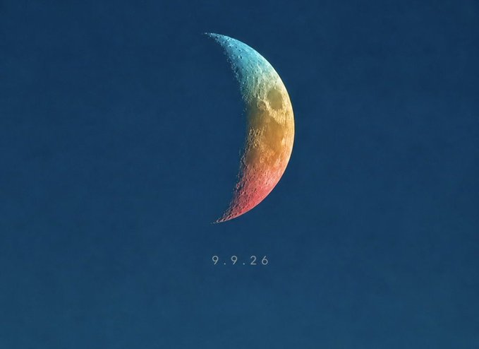 A photograph of a crescent moon against a dark blue sky, illuminated with multicolored hues of blue, orange, and pink, with the date '9.9.26' displayed below.