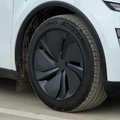Close-up photograph of a modern black alloy wheel with an aerodynamic spoke design mounted on a white vehicle.