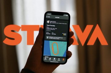 A hand holds a smartphone displaying the STEPN app, which shows a user's walk stats including 6,100 steps, with the orange "STEPN" logo overlaid across the image—visually reinforcing the post's idea that the app turns everyday walking into social contribution.