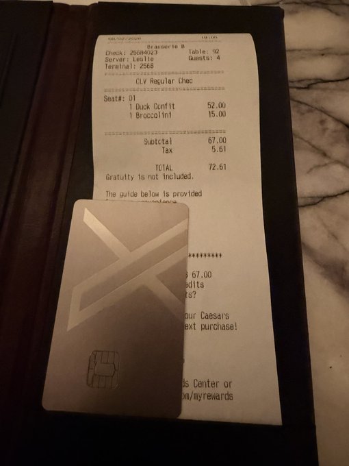 A restaurant receipt from a Caesars property in Las Vegas totals $72.61 for a duck confit and broccolini, resting beneath a credit card on a marble surface.