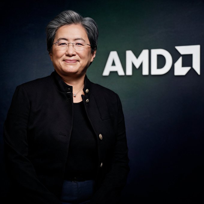 Dr. Lisa Su, CEO of AMD, stands smiling in front of the company's logo, an image fitting the post's celebration of AMD's stock surging nearly 10% to a record above $615 and pushing its market cap past $1 trillion on renewed AI semiconductor investor enthusiasm.