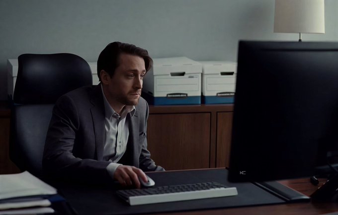 A man in a dark suit and light shirt sits at a desk, intently staring at a computer monitor with a frustrated or focused expression, his hand on the mouse. The caption connects to the post by illustrating the moment the "quick trade" turns into an extended stay—trapped at the screen long after the initial plan.