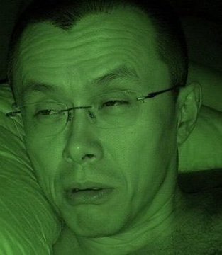 A close-up selfie of a man wearing glasses, captured with a night-vision green filter, showing a tired or weary expression as he rests on a pillow. The image likely conveys the exhaustion and late-night vigilance of a trader bracing for a turbulent week of market volatility, aligning with the "Green Monday" versus "Black Monday" sentiment described in the post.