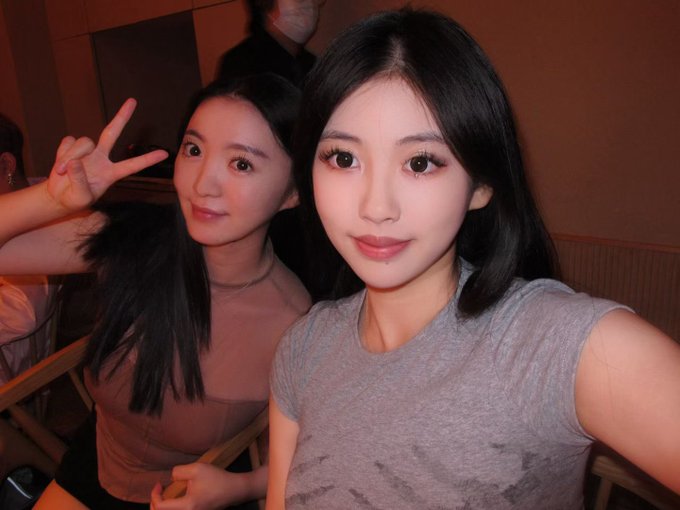 Two young women pose for a selfie at a restaurant, with the woman on the left flashing a peace sign while her bestie (likely @niu_shiqi115) leans in close, capturing a celebratory moment together over the dinner she treated her to.