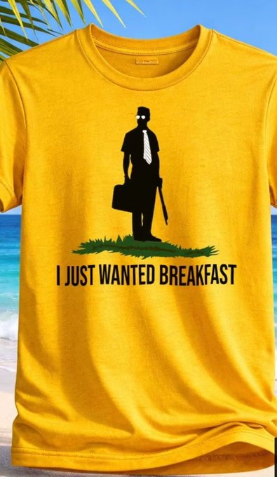 A yellow t-shirt displaying a silhouette of a businessman holding a briefcase and a gun, with the text 'I JUST WANTED BREAKFAST' on a beach background.