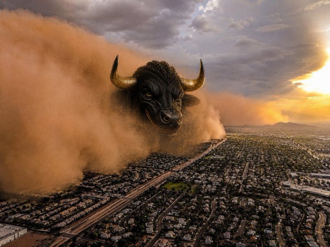 A dramatic scene of a massive bull head emerging from a dust storm over a sprawling suburban cityscape at sunset.
