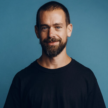 A bearded man with short hair, wearing a dark navy sweater, smiles slightly at the camera against a solid blue background. The image is a portrait of Jack Dorsey, the tech entrepreneur behind Block, whose new decentralized groupchat platform is highlighted in the post.