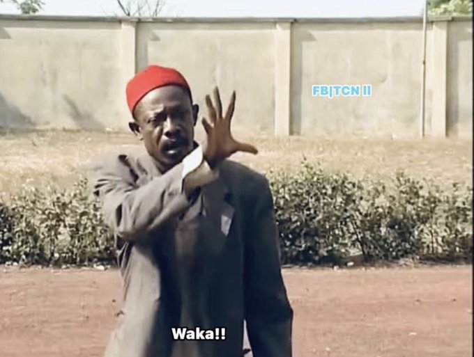 A man in a gray suit and red cap gestures dramatically with his hand raised outdoors, with the text 'Waka!!' visible at the bottom and 'FB|TCN||' watermark.