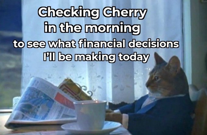 A cat in a suit sits at a table reading a newspaper with a coffee cup, captioned "Checking Cherry in the morning to see what financial decisions I'll be making today." The image humorously depicts the post's theme of starting the day by checking Cherry's content to guide financial decisions.