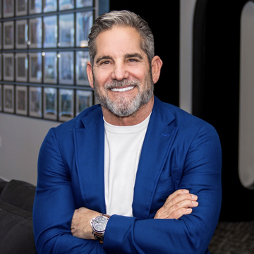 Grant Cardone, the entrepreneur and real estate investor, smiles confidently in a blue blazer and white t-shirt, projecting the approachable yet authoritative image of a financial commentator. His polished appearance complements the post's bold claim about U.S. homes being dramatically more affordable when measured in Bitcoin rather than dollars.