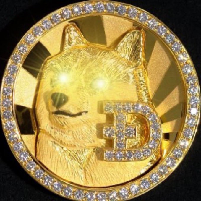 A gold coin with diamond-encrusted border featuring a Shiba Inu dog design holding a Bitcoin "₿" symbol in its mouth.