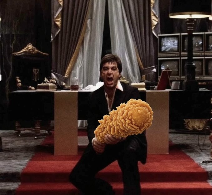 A dramatic scene of a man screaming while holding a large piece of fried chicken in an ornately decorated room with red carpeting and a desk.