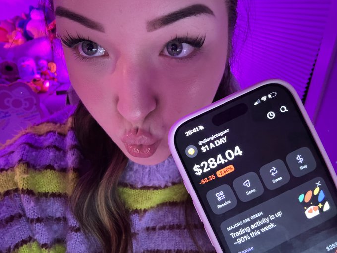 A close-up of a woman with long lashes puckering her lips beside a smartphone screen showing a crypto wallet with "$284.04" and a note that "Trading activity is up ~80% this week."