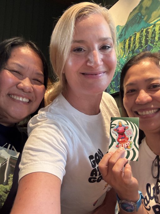 Three smiling women pose for a selfie, with the center blonde woman proudly holding up a Starbucks gift card featuring the "Dusty Cougar" merchandise design, celebrating her status as a "duster" alongside the hashtags and $UFD ticker referenced in the caption.