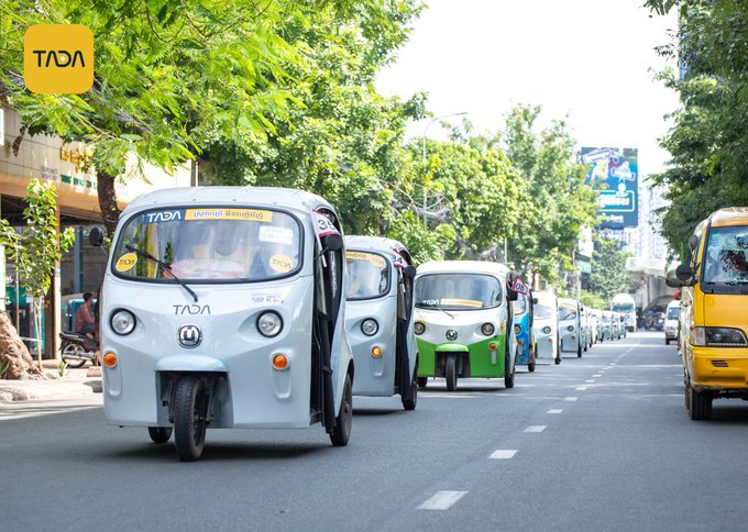 A fleet of white TADA auto rickshaws, prominently displaying the "TADA" logo and branding on their windshields and fronts, drives in a line down a tree-lined city street. The image visually reinforces the post's mention of TADA drivers, illustrating the real-world rides that generate daily cash flows backing Musubi's tokenized yield products.
