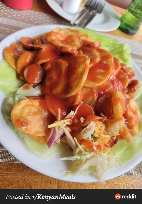 A plate of food featuring sliced sausages covered in red sauce, served over cabbage and coleslaw, posted to r/KenyanMeals on Reddit.