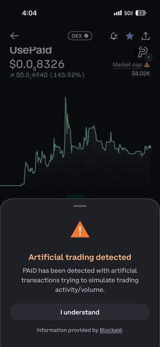 A crypto tracking app showing the 'UsePaid' (PAID) token at $0.8326 with a warning that 'Artificial trading detected' for the token.