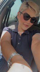 A woman with short blonde hair and sunglasses takes a selfie in a car, wearing a dark polo shirt and a silver watch, with no visible text or numbers in the image to relate to the "GM" (good morning) post.