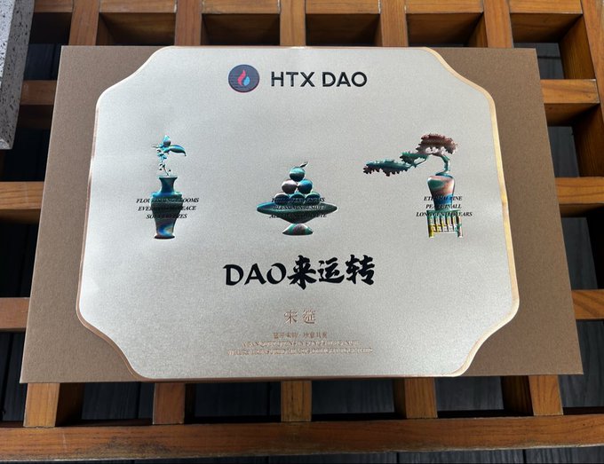 A decorative HTX DAO plaque with gold trim mounted on a wooden lattice, featuring three pixel art objects and the Chinese text 'DAO来运转' (DAO Will Turn).
