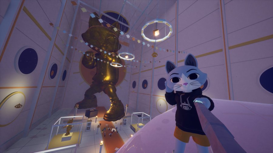In-game screenshot of a stylized cat avatar in a hoodie standing beside a giant golden statue in a tall, space-themed museum hall decorated with rings and banners.
