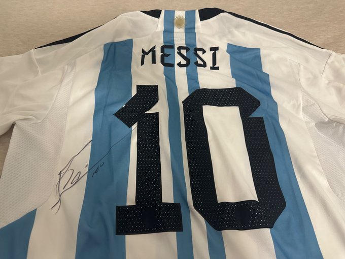 A light blue and white striped Argentina soccer jersey with 'MESSI' and the number 10 on the back, featuring a signature.