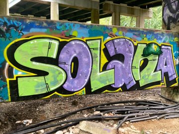 iced graffiti on a wooden beam, featuring the word "SOLA" in green and purple colors.