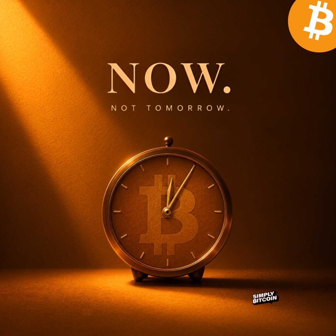 An advertisement-style image displays a golden alarm clock with a Bitcoin logo on its face, accompanied by the text "NOW. NOT TOMORROW." and "SIMPLY BITCOIN".