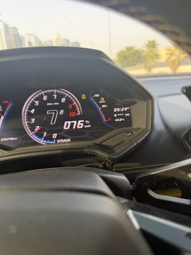 A close-up of a Lamborghini's digital dashboard showing a speed of 076 km/h and a fuel range of 0 km, with the caption highlighting the driver's risky 11-minute journey on empty fuel to refuel the car. The display confirms the precarious situation described in the post, emphasizing the tense moment of driving with no fuel remaining.
