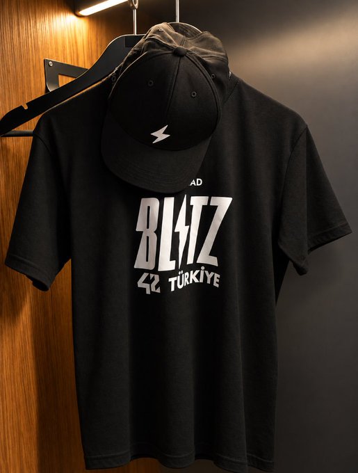 A black t-shirt and matching baseball cap hanging on a hanger, featuring 'BL4TZ' text and 'TÜRKIYE' lettering.
