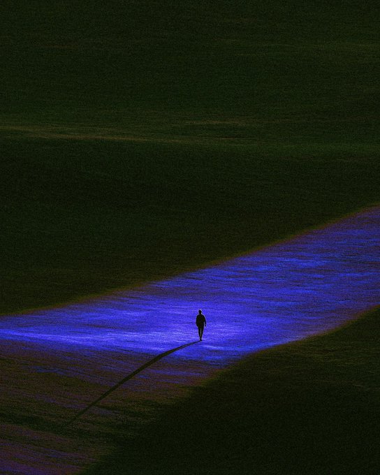 An artistic painting depicting a lone figure walking through a glowing blue path in a dark, greenish field, casting a long shadow.