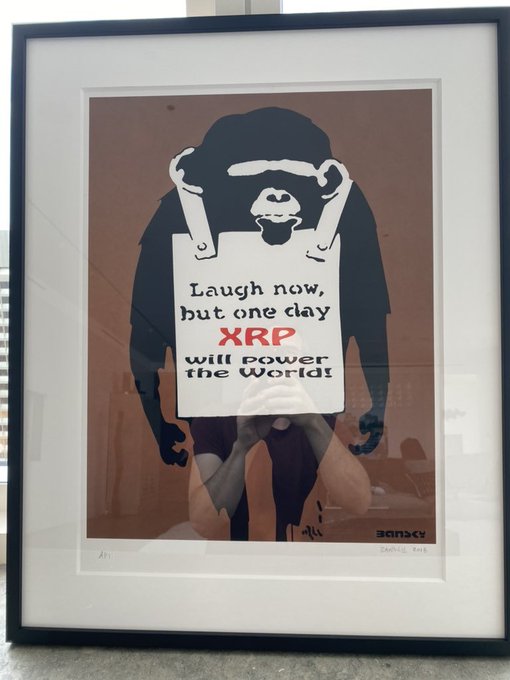 A framed Banksy-style print features a monkey holding a sign reading 'Laugh now, but one day XRP will power the World!'