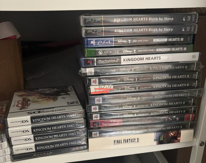 A collection of video games stacked on a shelf, predominantly featuring multiple copies of the Kingdom Hearts series for PlayStation 2, PSP, PS4, Xbox One, and Nintendo DS, along with a copy of Final Fantasy XI at the bottom.