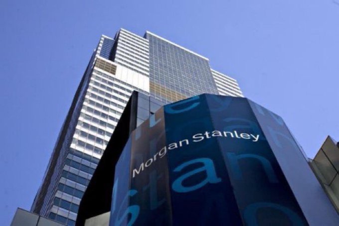 The image features a tall building with a large glass window that displays the name "Morgan Stanley" written on it. The building appears to be made of concrete or glass, depending on the angle from which you're viewing it. The sky is clear blue in color, providing a nice backdrop for the building's design and making the text on the building stand out prominently.