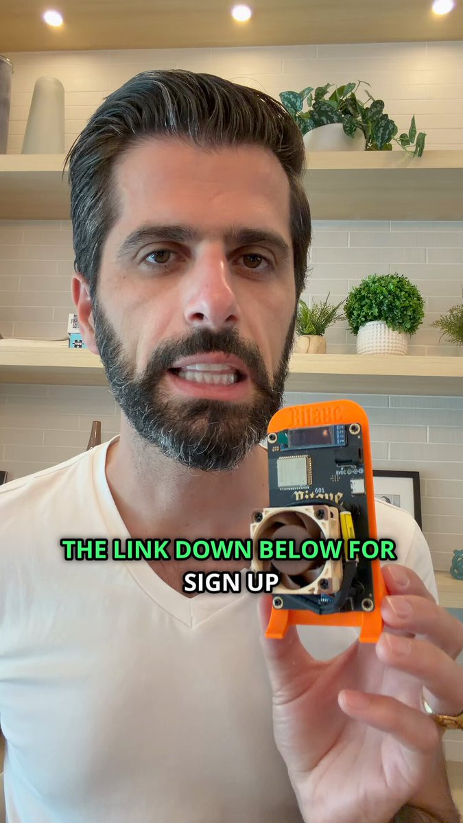The image features a man holding up an orange phone with a green screen protector, which has a message about a block reward of 3.1 Bitcoins. The man appears to be showing off his new phone or possibly explaining something related to Bitcoin mining.