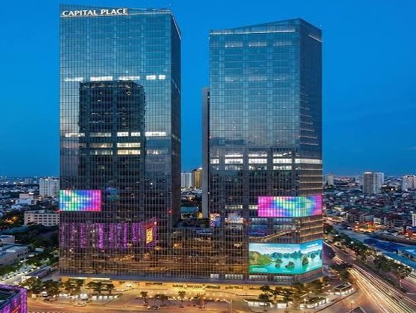 An aerial view of Capital Place in Ho Chi Minh City, Vietnam, featuring two glass skyscrapers displaying colorful digital screens.