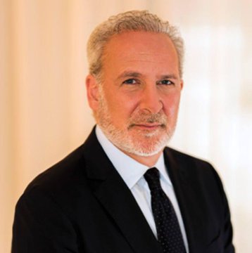 A middle-aged man with gray hair and a beard, wearing a black suit, light blue shirt, and patterned tie, poses for a professional portrait.