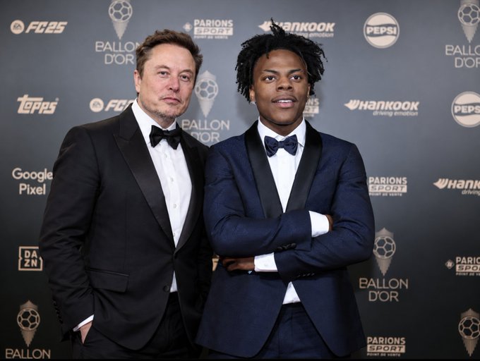 Elon Musk and a young man in a tuxedo pose together on a red carpet at the Ballon d'Or event, with sponsor backdrops visible for EA FC 25, Hankook, Pepsi, Google Pixel, and DAZN.