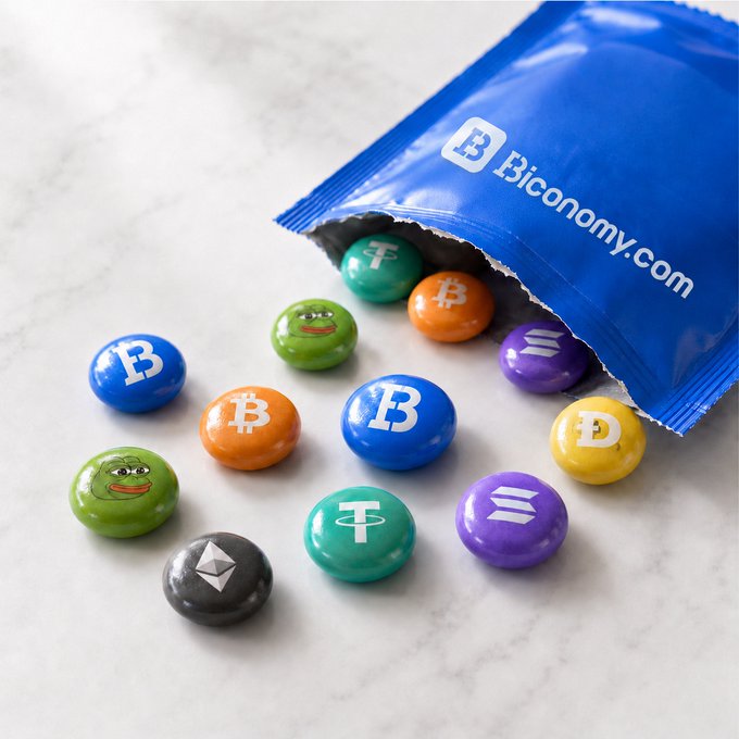 A blue "Biconomy.com" bag spills colorful candy coins on a marble surface, each labeled with crypto tickers (BTC, ETH, SOL, USDT) and a Pepe meme token—visually matching the post's playful "pick your candy" lineup of digital assets.