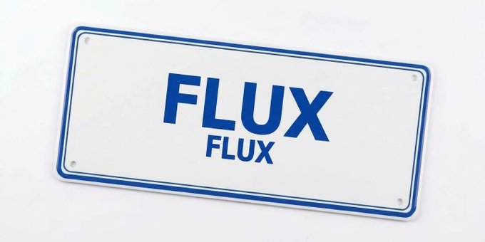 A white rectangular sign or license plate with a blue border, featuring the word 'FLUX' printed in large blue letters above the same word in a smaller font.